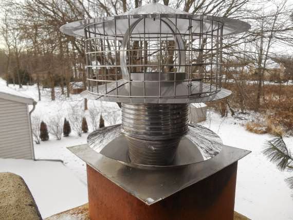 Liner on chimmney Installed With New Chimney Cap snow on ground and trees in the background